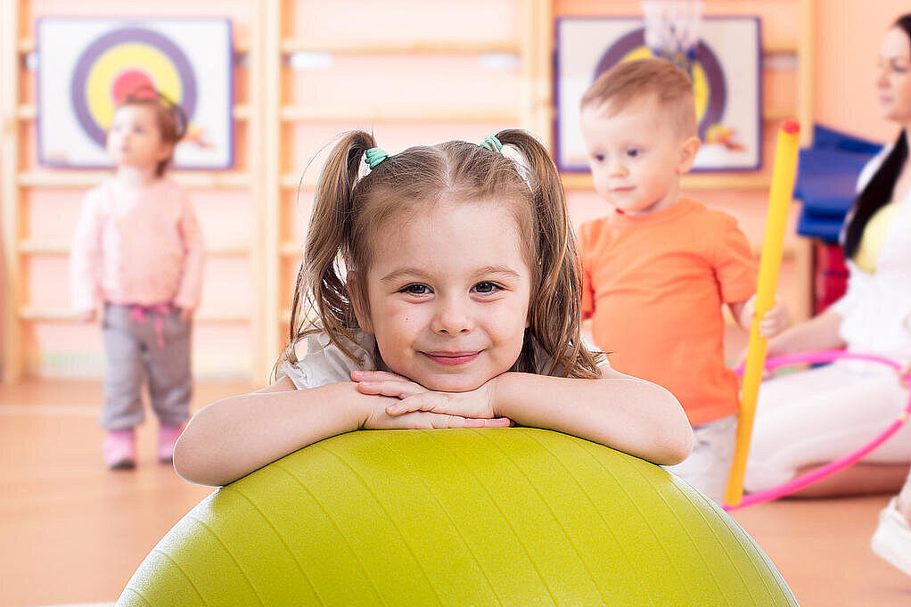 Smiling pretty child with fitness ball in gym