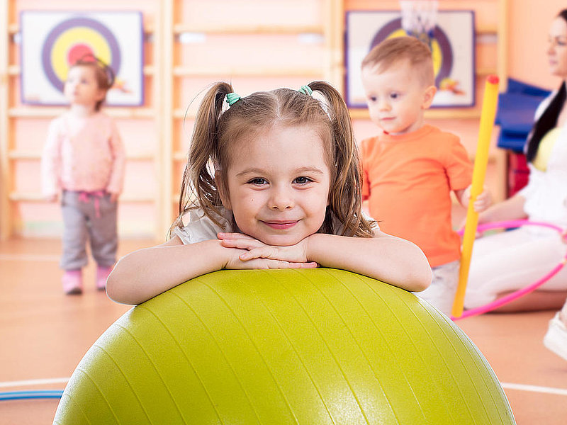 Smiling pretty child with fitness ball in gym